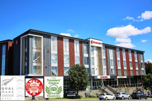 un grand bâtiment avec des voitures garées devant lui dans l'établissement Ramada Suites by Wyndham Albany, à Auckland