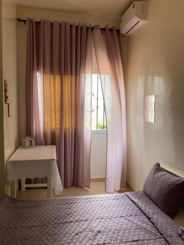 a bedroom with a bed and a window with a table at Chez Camille a Zac Mbao in Diokoul