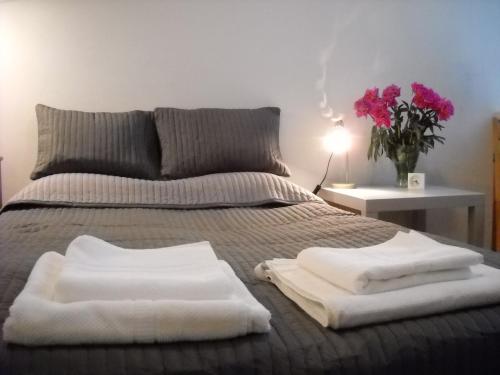 łóżko z dwoma białymi ręcznikami na górze w obiekcie A może na Pańskiej? w Warszawie