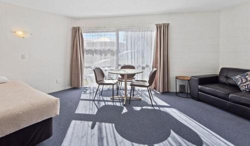 una camera con tavolo, sedie e divano di Motel Six a Whangarei