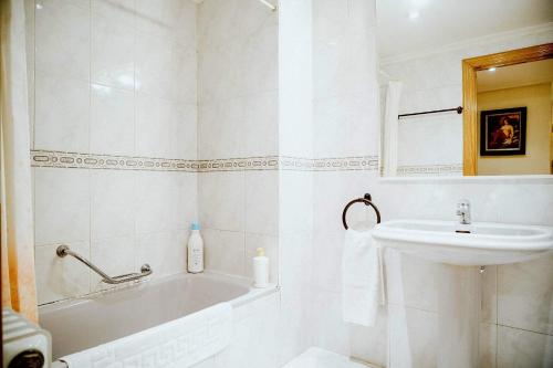 bagno bianco con lavandino, vasca e servizi igienici di Apartamentos GARDEN a Salamanca