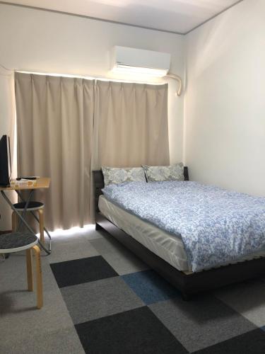 1 dormitorio con cama, mesa y TV en ジンジャー en Isla Miyako