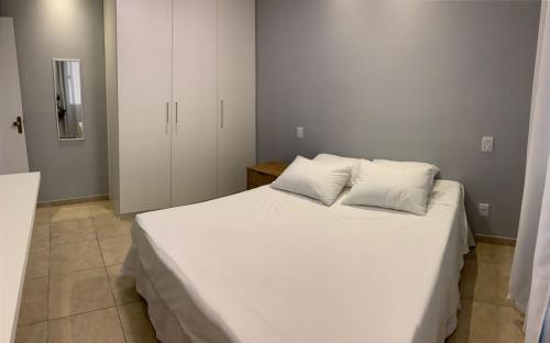 um quarto com uma grande cama branca e 2 almofadas em Apartamento ao lado da UFOP com garagem em Ouro Preto