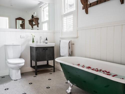 y baño con bañera verde y aseo. en The Little School House, en Hepburn Springs