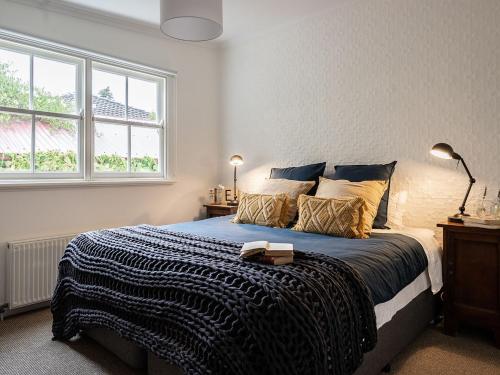 um quarto com uma cama com um cobertor azul e uma janela em The Little School House em Hepburn Springs