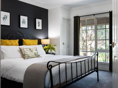 a bedroom with a bed with black walls and yellow pillows at Lucini Cottage in Hepburn Springs