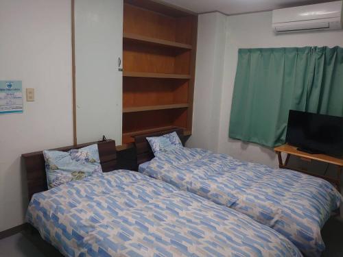 a bedroom with two beds and a television in it at ジンジャー in Miyako-jima