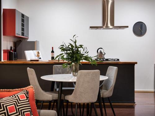 a table with chairs and a vase with a plant at Minni Gums- a perfect romantic getaway in Daylesford