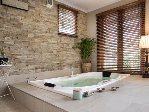 uma banheira num quarto com uma parede de pedra em The Acorn em Daylesford