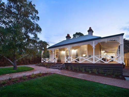 a large white house with a porch on a lawn at Dunroman - modern comfort, old world charm in Daylesford