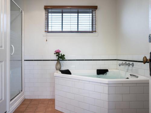 a white bathroom with a tub and a window at Churchills in Daylesford