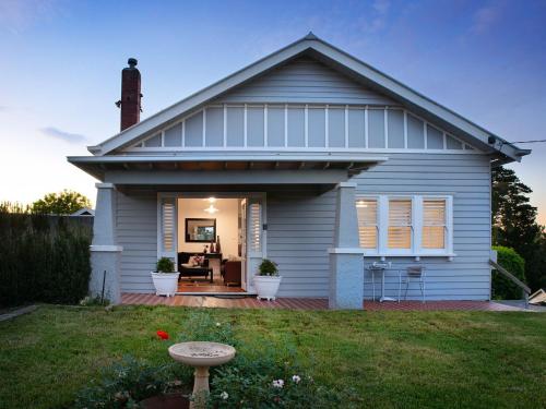 a white house with a porch and a patio at Churchills - outstanding views over Daylesford in Daylesford