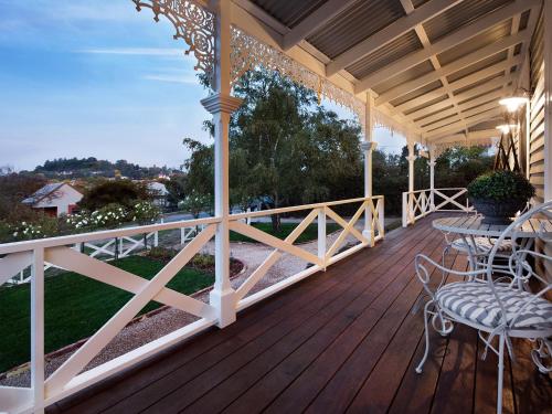 a wooden porch with a table and chairs on it at Dunroman - modern comfort, old world charm in Daylesford