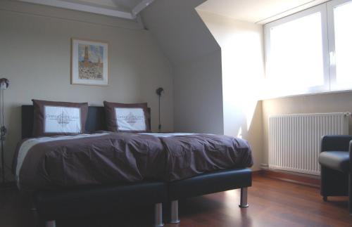 a bedroom with a bed with a chair and a window at B&B Bru-Beauline in Bruges