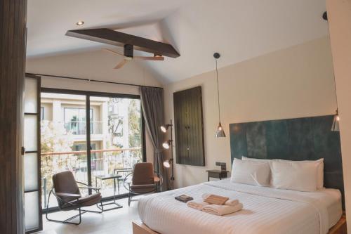 a bedroom with a bed and a balcony with chairs at Gategaa Village in Chiang Mai