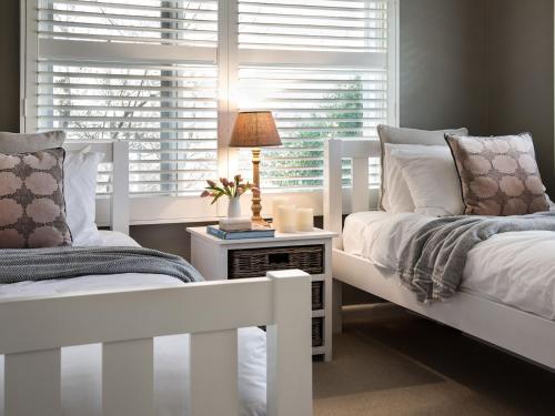 a bedroom with two white beds and a window at Green Gully House - a scenic country retreat in Glenlyon