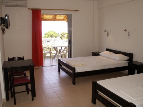 una camera con due letti, un tavolo e una sedia di Kastro Beach Hotel a Kyllini
