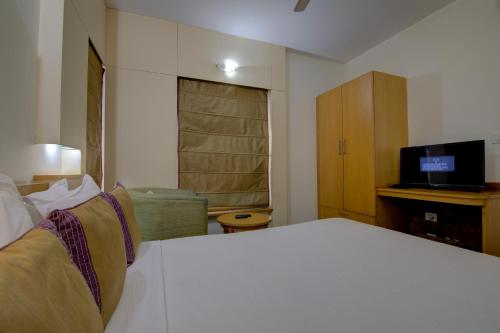 a bedroom with a white bed and a television at Tristar Serviced Apartments in Bengaluru