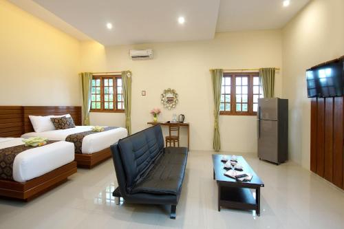 a bedroom with two beds and a couch and a table at S5 Guest House Yogyakarta in Yogyakarta