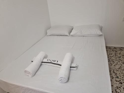 białe łóżko z dwoma ręcznikami bejsbolowymi w obiekcie דירה במדבר w Ejlat