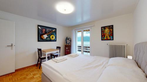 a bedroom with a white bed and a table at Modern and charming apartment on the shores of Lake Lucerne in Gersau