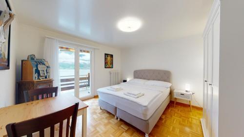 a bedroom with a bed and a table and a window at Modern and charming apartment on the shores of Lake Lucerne in Gersau