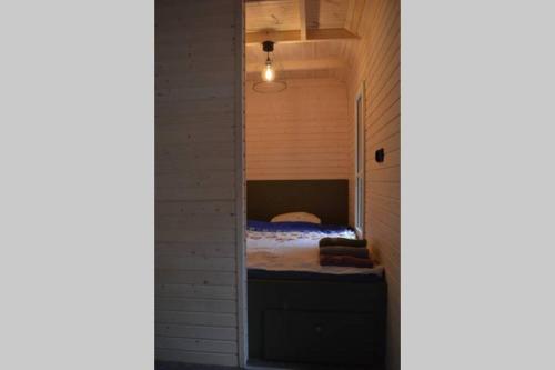 een kleine slaapkamer met een bed in een bakstenen muur bij heather hut, off-grid cottage on a pond+2 ha in Darżkowo