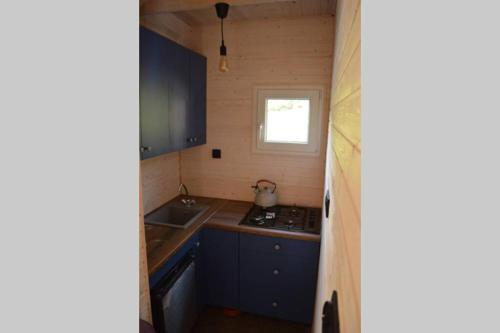 een kleine keuken met blauwe kasten en een wastafel bij heather hut, off-grid cottage on a pond+2 ha in Darżkowo