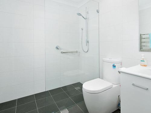 een witte badkamer met een douche en een toilet bij Burraneer at Corlette in Corlette