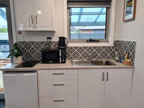 a kitchen with white cabinets and a sink and a window at Kadi House - Unit 1 in Wynyard