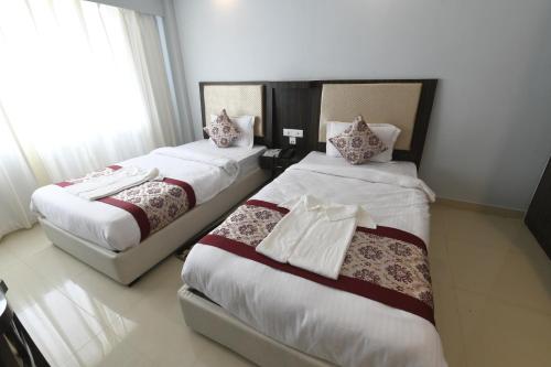 two beds in a hotel room with white sheets at Hotel Star Bodh Gaya in Bodh Gaya