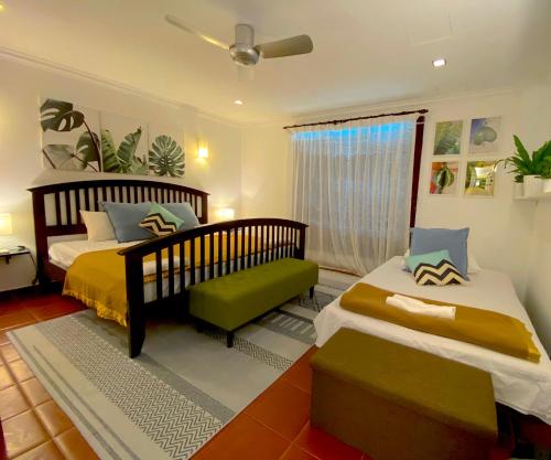 a bedroom with two beds and a chair and a window at 12Haven Stunning Seaside Luxury Villa PD with Kids Pool in Port Dickson