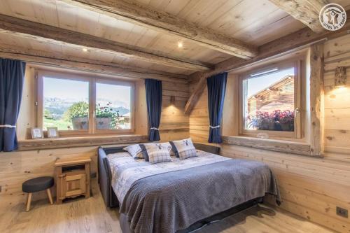 1 dormitorio con 1 cama y 2 ventanas en Le Granit, en Combloux