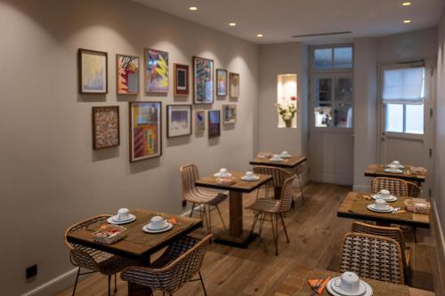 un restaurante con mesas, sillas y cuadros en la pared en Hôtel du Danube Saint Germain, en París