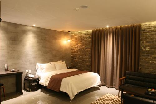 a bedroom with a bed and a brick wall at Hotel Banwol Asiad in Incheon