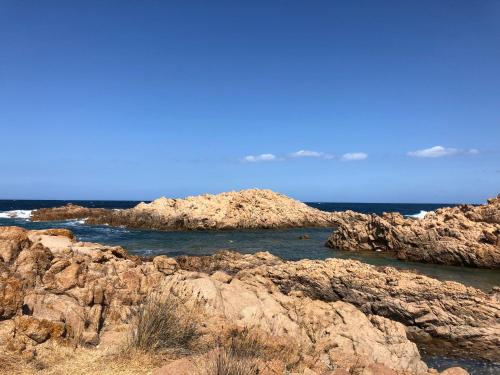 a group of rocks in the ocean with the water at CASA LA TANCA in Isola Rossa