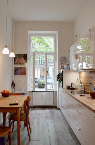 uma cozinha com armários brancos, uma mesa e uma janela em Dunckerstr. em Berlim