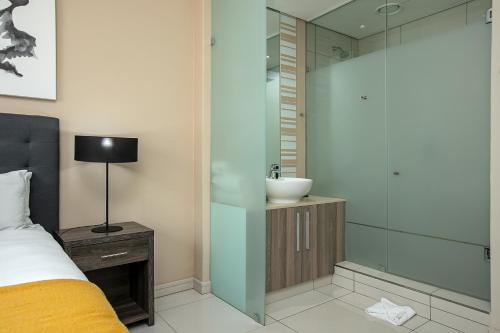 a bedroom with a sink and a glass shower at The Serviced Apartment Collection At The Tyrwhitt Rosebank in Johannesburg
