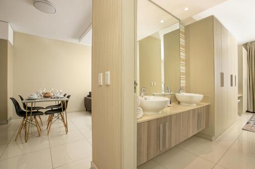 a bathroom with two sinks and a table at The Serviced Apartment Collection At The Tyrwhitt Rosebank in Johannesburg
