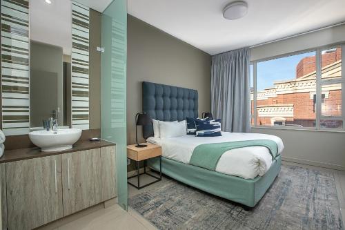 a bedroom with a bed and a sink and a window at The Serviced Apartment Collection At The Tyrwhitt Rosebank in Johannesburg