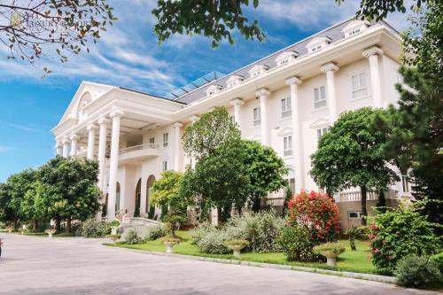 a large white building with trees and flowers at FLC Luxury Resort Vinh Phuc in Hoằng Xá