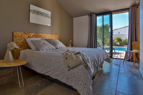 une chambre avec un lit et une vue sur une piscine dans l'établissement Villa Brigitte, à La Couarde-sur-Mer
