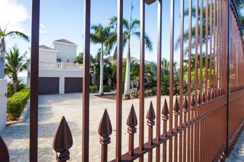 a fence with palm trees in front of a house at Sandcastle Villa & Beach House in The Valley