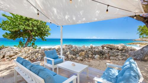 a patio with chairs and a table and the beach at Sandcastle Villa & Beach House in The Valley