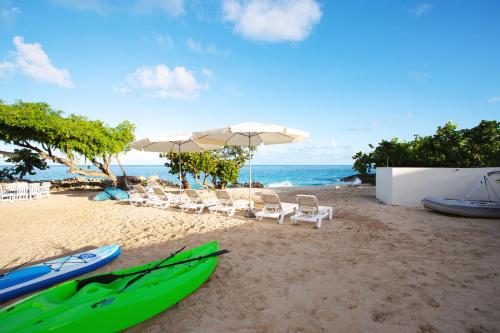 a beach with chairs and umbrellas and a group of kayaks at Sandcastle Villa & Beach House in The Valley