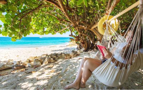 a woman sitting in a hammock on the beach at Sandcastle Villa & Beach House in The Valley