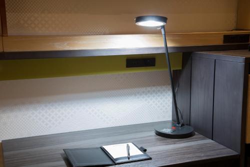 a desk with a lamp and a book on a table at Shizutetsu Hotel Prezio Kyoto Karasumaoike in Kyoto