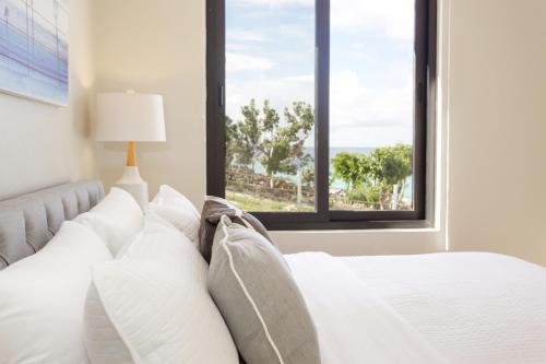 a bedroom with a bed with white pillows and a window at Sandcastle Villa & Beach House in The Valley