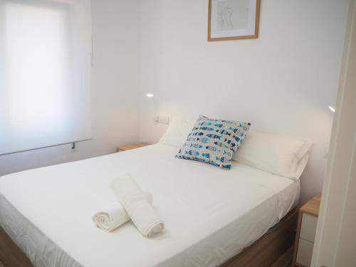 ein weißes Bett mit zwei gewalzten Handtüchern darauf in der Unterkunft Apartament amb piscina i aparcament - Baixos amb jardinet in Calella de Palafrugell