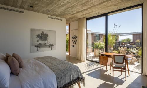 a bedroom with a bed and a desk and a large window at Posada Ayana - Adults Only in José Ignacio